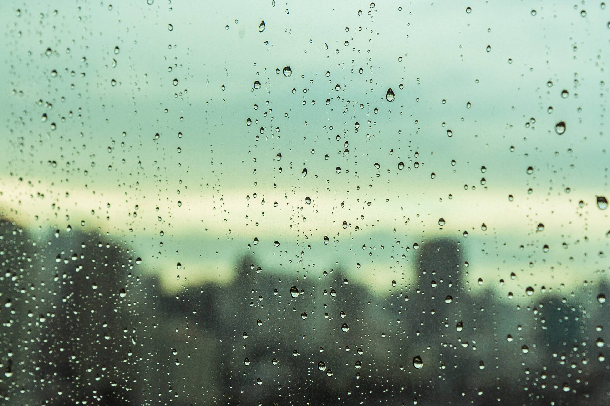 rain on the windows of an office town looking out onto a blurred city backdrop