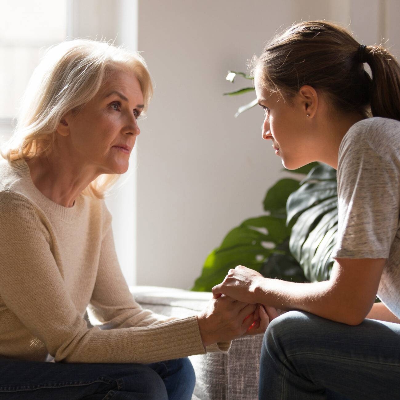 two women sitting across from each other comforting each other